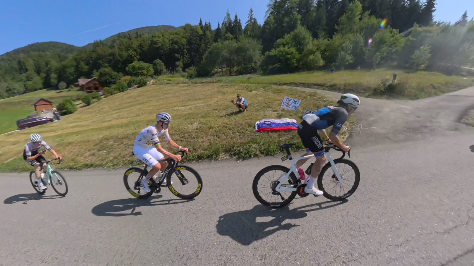 Rodrigo and two riders climbing past a Slovenian flag on a mountain road