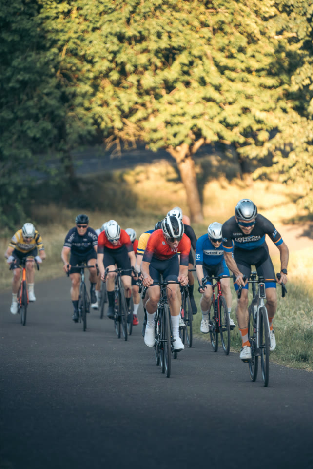 Rodrigo riding at the front of a group on a tree lined road